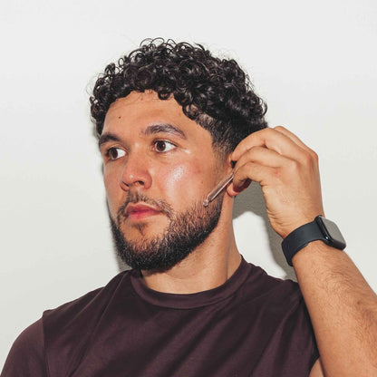 Man with a beard using Beardoil against a plain background