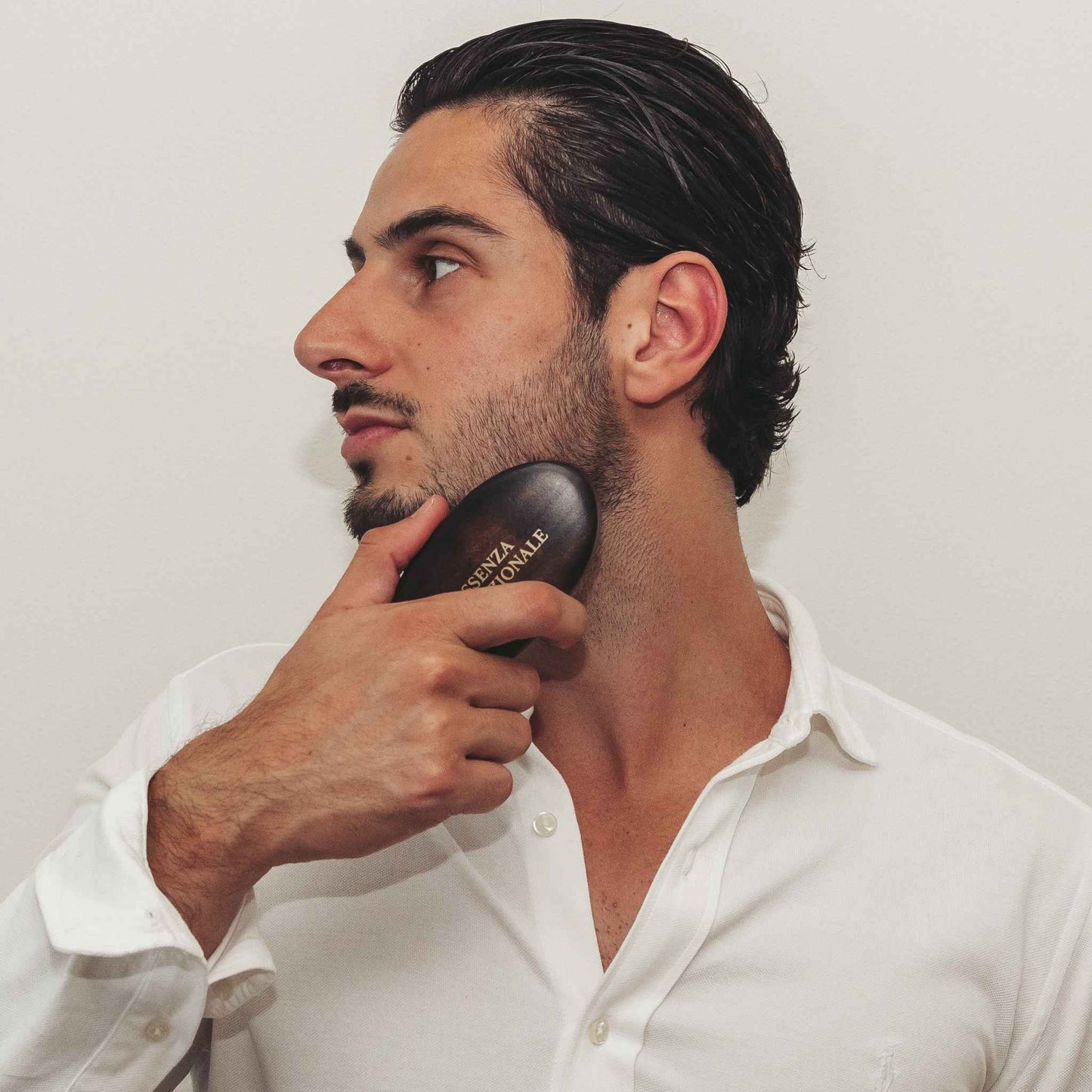 Man using a Beardbrush on his beard against a plain background