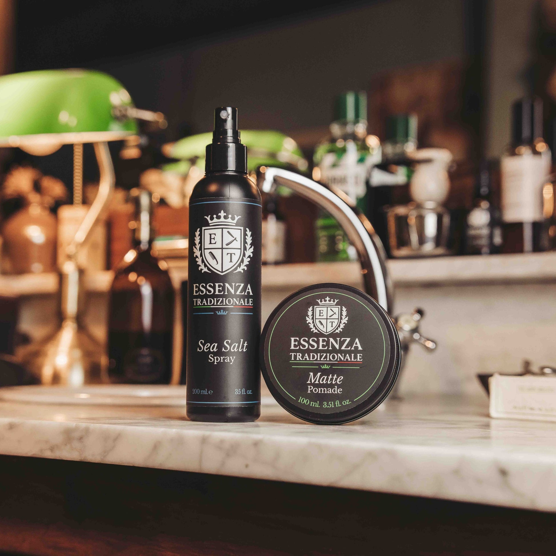 Two bottles of Essenza Tradizionale products on a marble countertop with a blurred bar background.