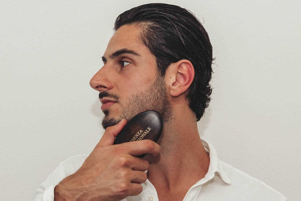 Man using a hairbrush on his neck against a plain background